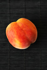 One ripe peach in on a black background. Summer fruit