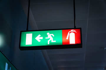 Emergency fire exit sign glowing green in the blacked out background at airport