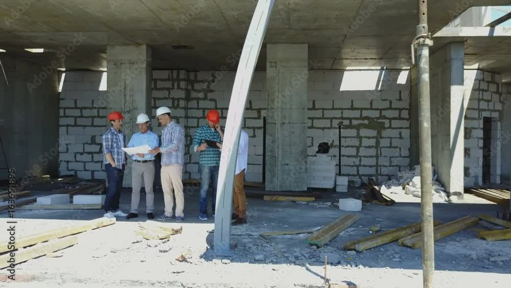 Poster aerial shot of builders team on construction site discussing plan of project with architect and cont