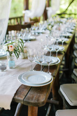 Glasses and plates on the festive wooden table. Wedding table decor concept. Table setting in classic style, setout. fine art.