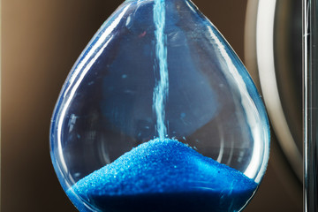 Time is passing. Blue hourglass close up