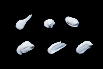 Collection of various strokes of shaving cream on black background