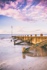 Fototapeta premium Sunset view of Edinburgh's Portobello Beach with wooden groynes. Scotland, United Kingdom