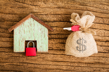 Home model and a money and key put on the wooden vintage background, Buying a new house and real estate concept.