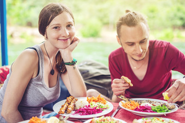 young couple eats vegetables and fish outdoors in a cozy restaurant on the water, opens new kitchen