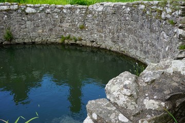 Fototapeta na wymiar Ancient stone cistern filled with water