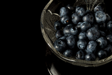 A pile of blueberries in a glass bowl isolated on black background