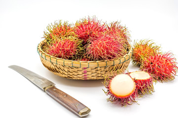Fototapeta na wymiar fresh tropical rambutan fruits over basket with knife on a white background, fruit in Thailand