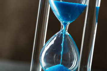 Time is passing. Blue hourglass close up