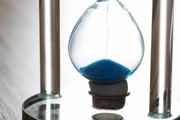 Time is passing. Blue hourglass close up