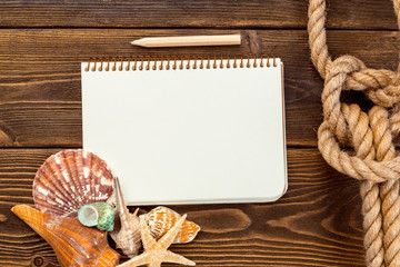 Shells and notepad on wooden table. Top view with copy space