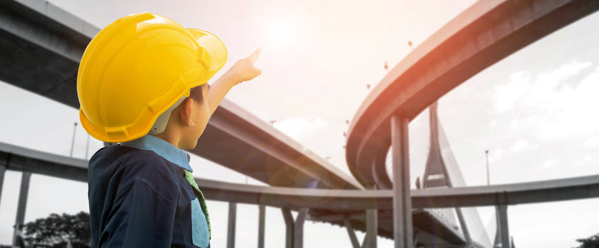 Panoramic of a boy wearing a helmet is pointing his hand to the highway.- Construction industry and transportation concepts.can use for web banner.