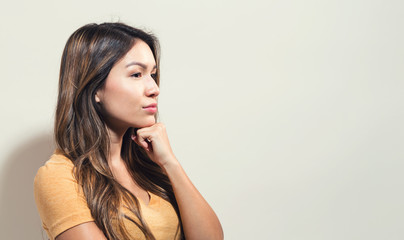 Young woman in a thoughtful pose on a off white background