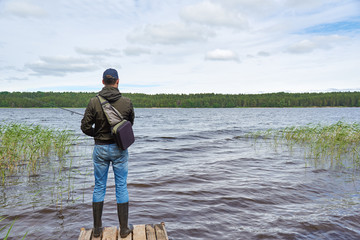 Fototapeta na wymiar Man fishing with spinning rod in a lake.