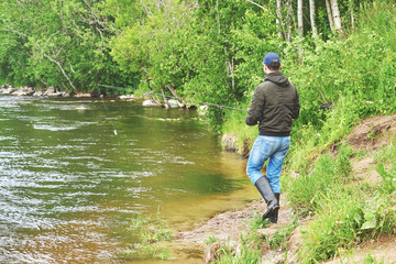 Fototapeta na wymiar Man fishing with spinning rod in a rapid river.