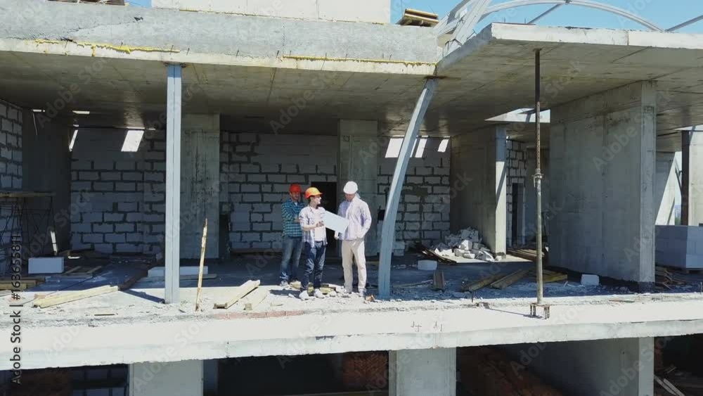 Poster aerial shot of builders team on construction site discussing plan of project with architect and cont