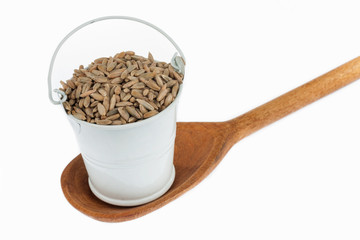 Full bucket of rye grains stands in a wooden spoon.