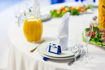 Table set for wedding banquet with cutlery. Salads, appetizers and glasses for wine. Decoration elements - vases with orange slices and white chrysanthemum flowers.