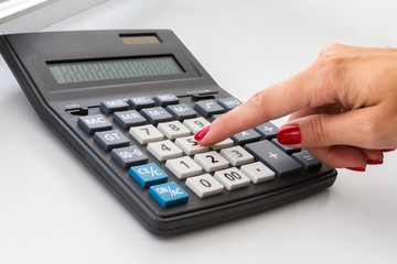 hand with the calculator on the desktop, close up