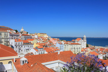 Naklejka na ściany i meble Beautiful panoramic wallpaper of Miradouro Portas do Sol viewpoint in Lisbon, Portugal. Rooftop view of Alfama old town historical district on summer time