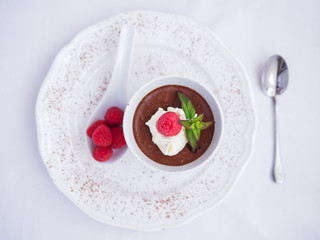 Chocolate mousse with raspberry and cream, dressed with mint leaves.