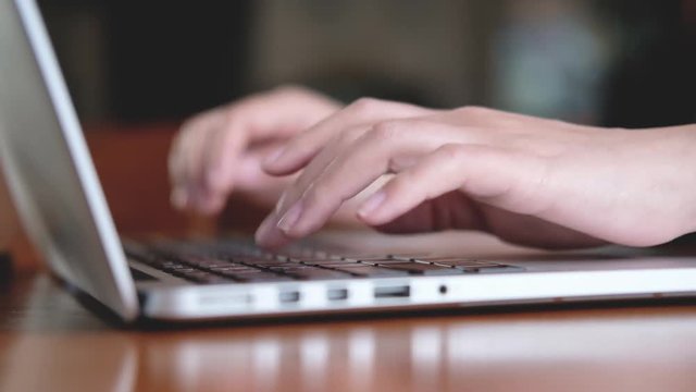 Closeup image of a business woman's hands working and typing on laptop keyboard on wooden table in office