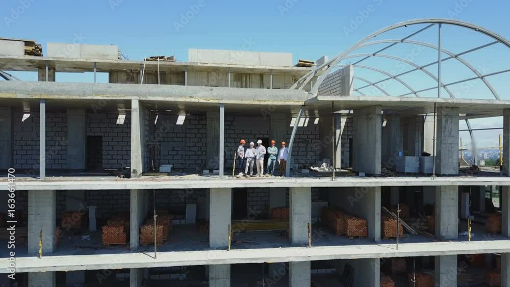 Poster aerial shot of builders team on construction site discussing plan of project with architect and cont