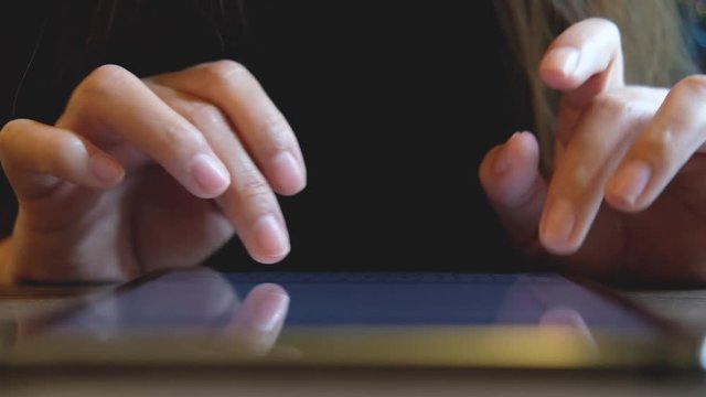 A woman's hands touching and typing on tablet pc with blur background in cafe