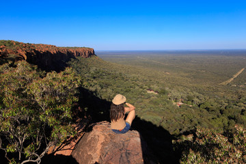 Girl sitting on stone on the cliff at an african landscape. Waterberg plateau, Namibia