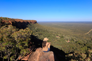 Girl sitting on stone on the cliff at an forest landscape.