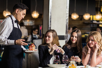 Close up of waiter hand noting down menu on tablet. Young woman ordering for food to a waiter at...