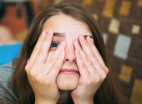 The Girl Covers Her Face With Hands So That One Could See One Eye. Fooling Around At Home