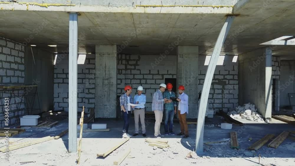 Poster aerial shot of builders team on construction site discussing plan of project with architect and cont