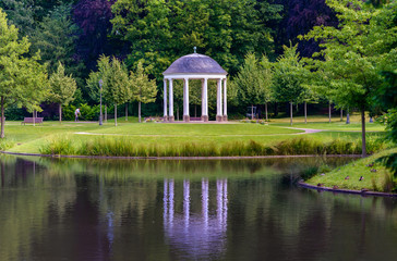 Domed gazebo in a lush ark reflected in a lake