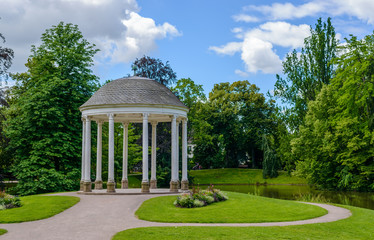 Domed gazebo in a lush ark reflected in a lake