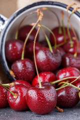 Red cherry in an enameled mug on a background of textile sackcloth.