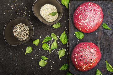Pink buns for the vegetable Burger on the basis of beet with sesame seeds on dark background. Top view