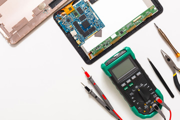 Fototapeta premium Multimeter and broken tablet, electronics at repair shop