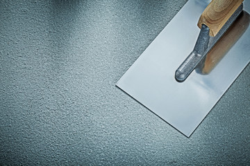 Stainless plastering trowel on concrete background construction 