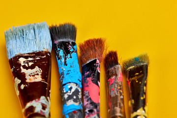 Vintage artists brushes with paint on an yellow background.Closeup.Copy space
