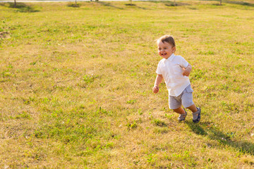 Happy baby boy running on summer field