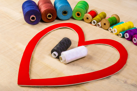 Heart in the center of which black and white threads lie on a wooden table