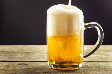 Pouring beer into a glass on a wooden table. Alcoholic beverages. Alcohol-free beer. Sale of beer to the bar.