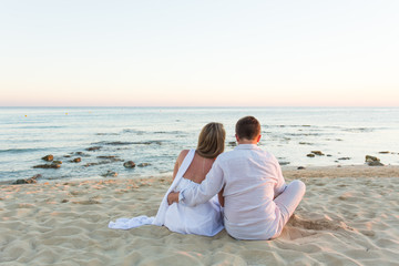 Young love couple sitting together on beach