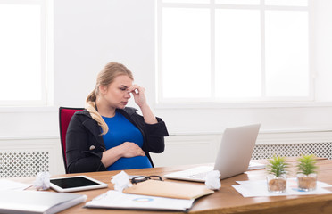 Pregnant woman working on laptop at office