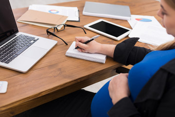 Pregnant woman writing note on her workplace