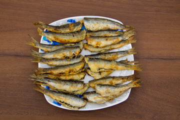 Fried baltic herring on a plate on wooden background