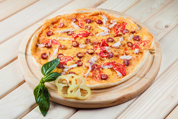 Pizza with salami on the wooden background