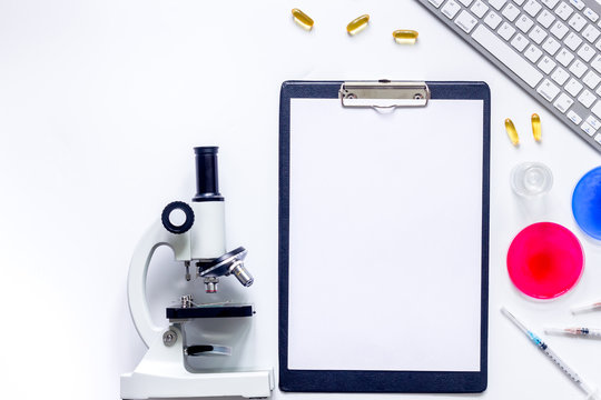 Medical tests. Work table of doctor witn microscope, Petri dish, syringe on white background top view copyspace mockup