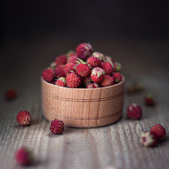 strawberries in wooden bowl over dark background, rustic style, close up